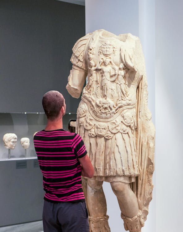 Tourist viewing ancient statue at Heraklion Archaeological Museum, Crete, Greece.