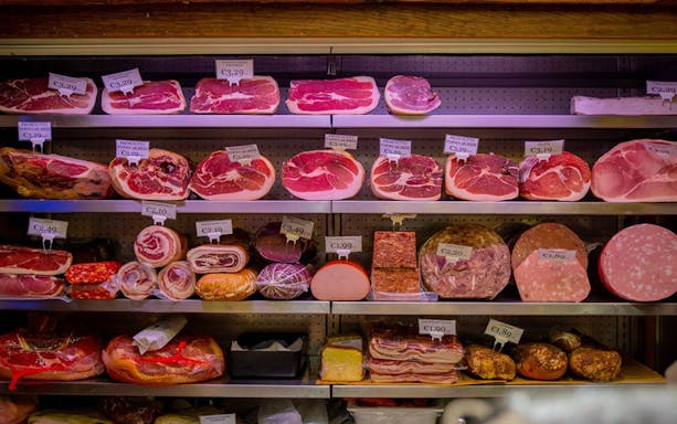 Cured meats and salami on display in a Bologna deli during a walking tour tasting.