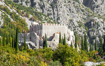 Sokol grad fortress surrounded by trees and rocky hills in Croatia.
