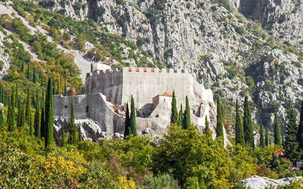 Sokol grad fortress surrounded by trees and rocky hills in Croatia.