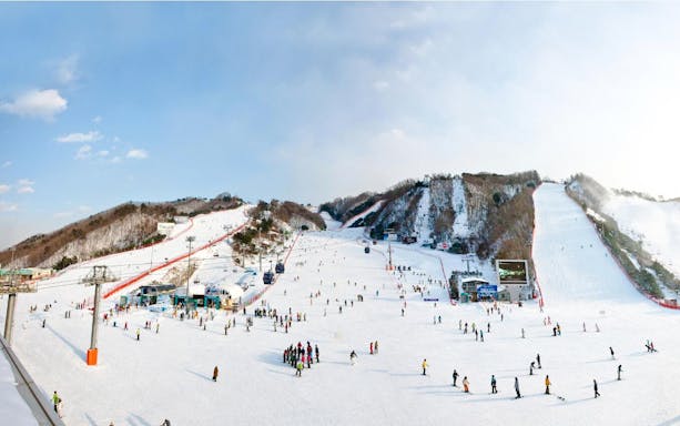 Tourists skiing and snowboarding at Vivaldi Park Ski World in South Korea.