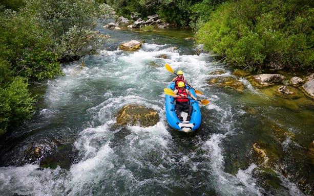 Rafting on a river with lush greenery during the Rapid Rafting tour from Split.