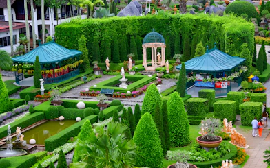 Nong Nooch Tropical Garden with manicured hedges, statues, and gazebos in Pattaya, Thailand.
