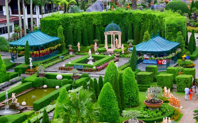 Nong Nooch Tropical Garden with manicured hedges, statues, and gazebos in Pattaya, Thailand.