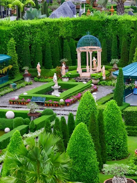 Nong Nooch Tropical Garden with manicured hedges, statues, and gazebos in Pattaya, Thailand.