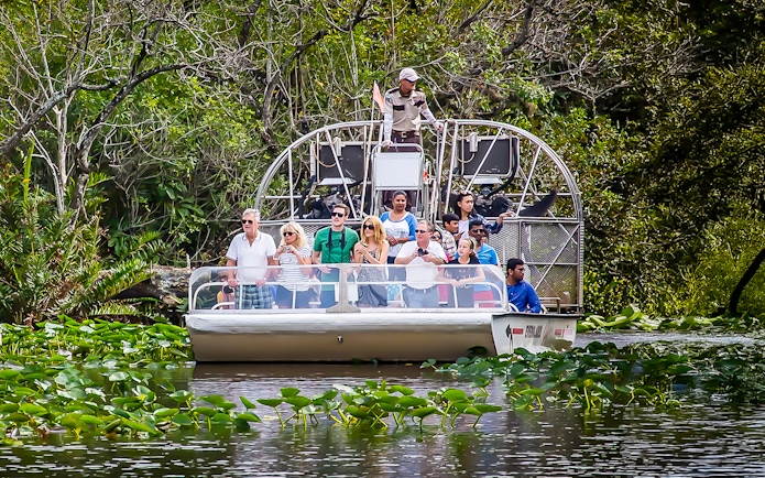 Guests on an airboat tour in Everglades National Park surrounded by lush greenery.