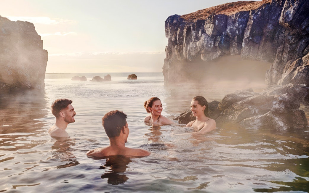 Guests enjoying geothermal waters at Sky Lagoon, Iceland, surrounded by rocky cliffs.
