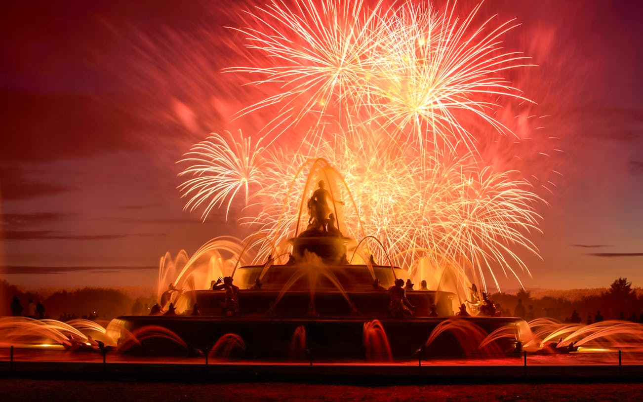 Versailles fountain illuminated by fireworks during night show from Paris.