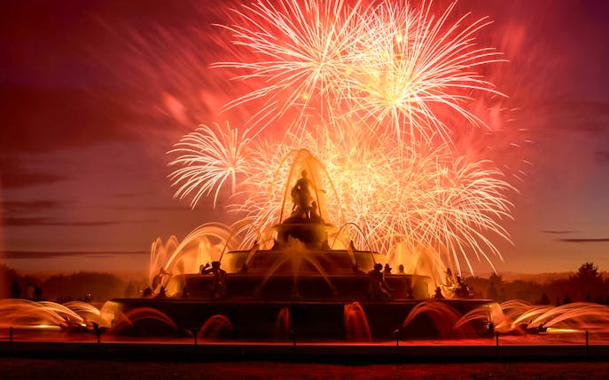 Versailles fountain illuminated by fireworks during night show from Paris.