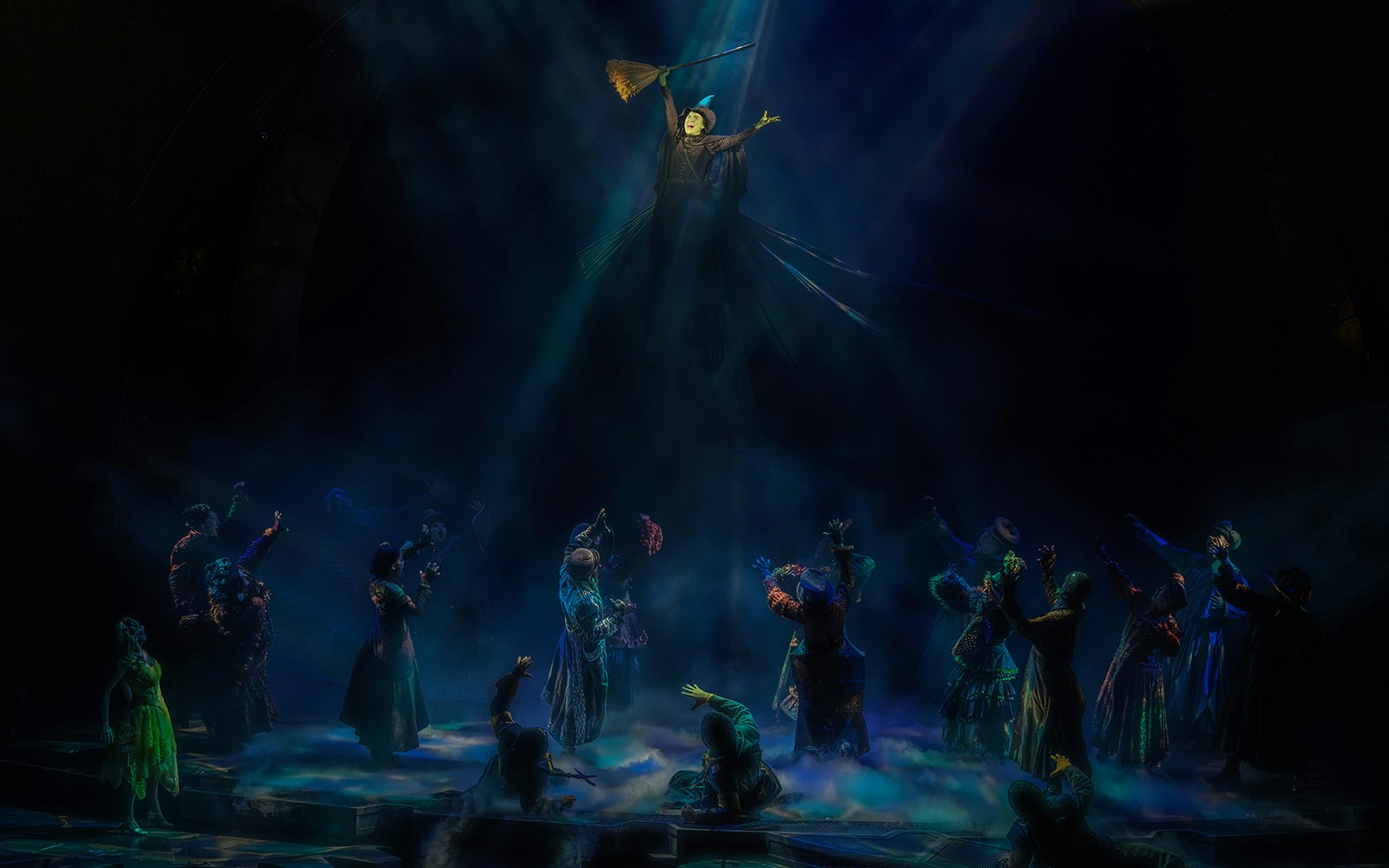 Stage scene from the musical Wicked with characters in dramatic lighting.
