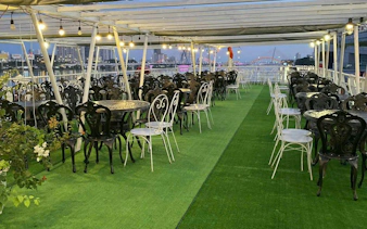 Outdoor dining area on a boat with views of the Han River and Dragon Bridge in Dubai.