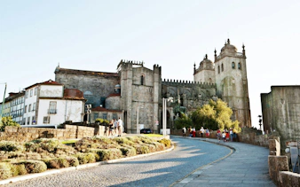 Porto Cathedral with tourists walking along the cobblestone path, part of a self-guided city exploration game.