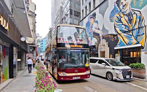 Double-decker bus on Hong Kong street with colorful mural, part of Big Bus Tour.