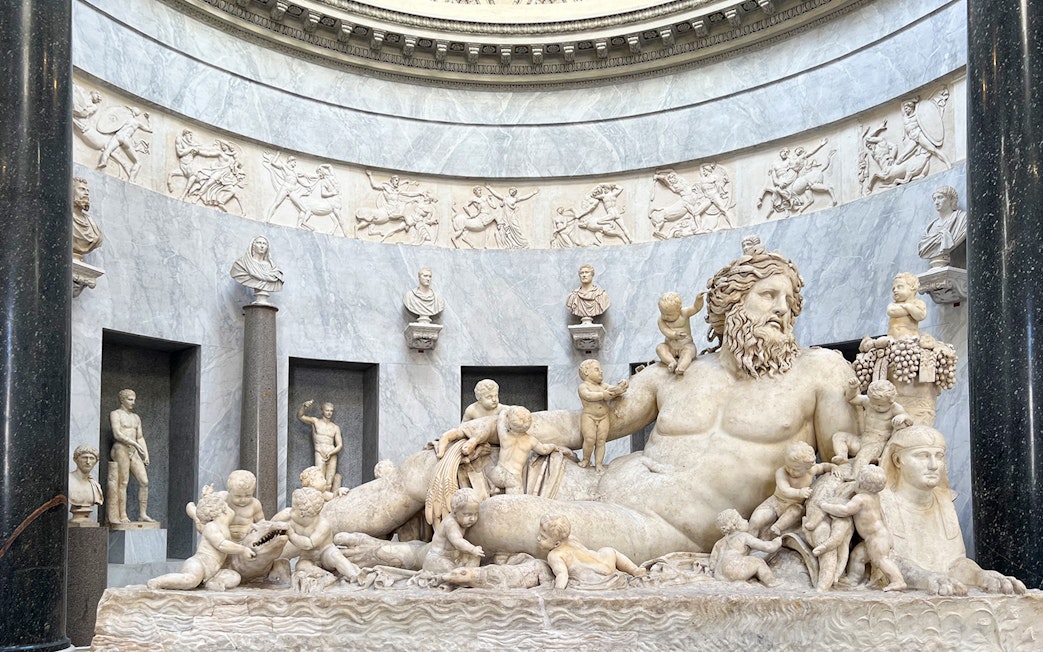 Statue of river god Oceanus surrounded by figures in Vatican Museums.