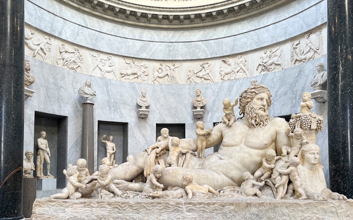 Statue of river god Oceanus surrounded by figures in Vatican Museums.