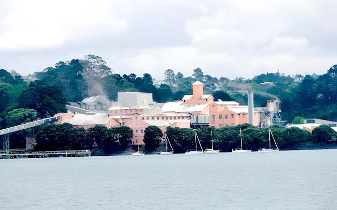 Harbour view with boats and a pink building surrounded by trees on a scenic wine and cheese cruise.