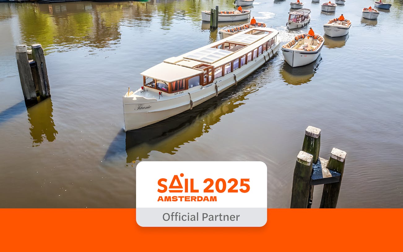 Saloon boat cruising on Amsterdam canal with other boats nearby.