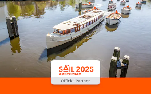Saloon boat cruising on Amsterdam canal with other boats nearby.