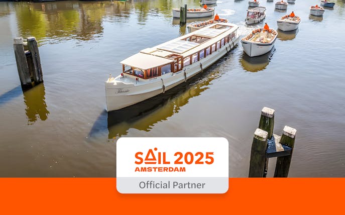 Saloon boat cruising on Amsterdam canal with other boats nearby.