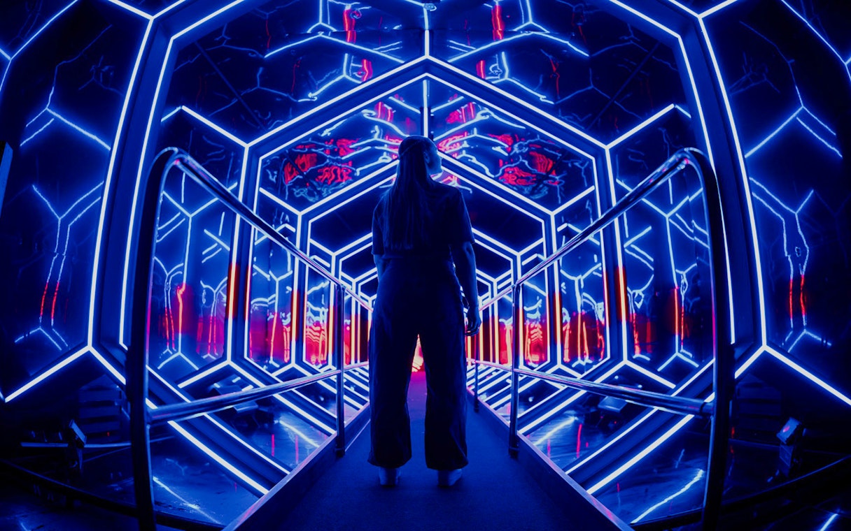 Visitor exploring neon-lit tunnel at Amaze Amsterdam.