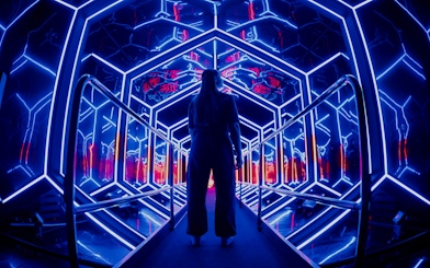 Visitor exploring neon-lit tunnel at Amaze Amsterdam.