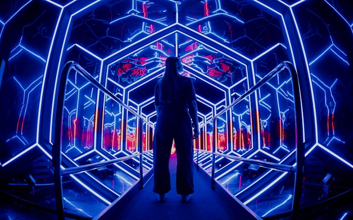 Visitor exploring neon-lit tunnel at Amaze Amsterdam.