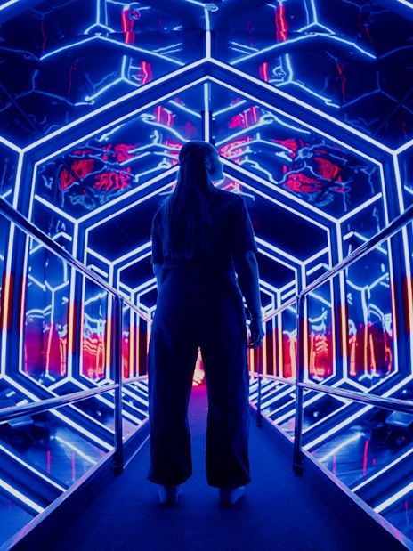 Visitor exploring neon-lit tunnel at Amaze Amsterdam.