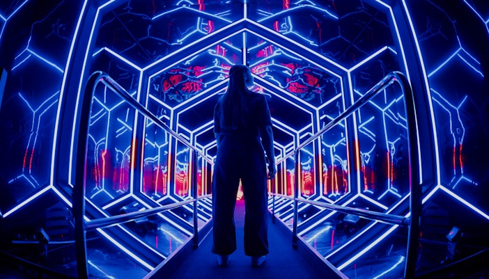 Visitor exploring neon-lit tunnel at Amaze Amsterdam.
