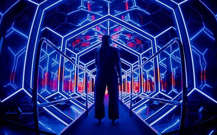 Visitor exploring neon-lit tunnel at Amaze Amsterdam.