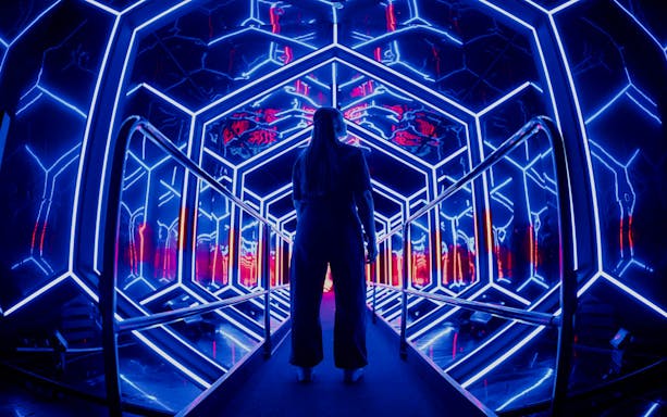 Visitor exploring neon-lit tunnel at Amaze Amsterdam.