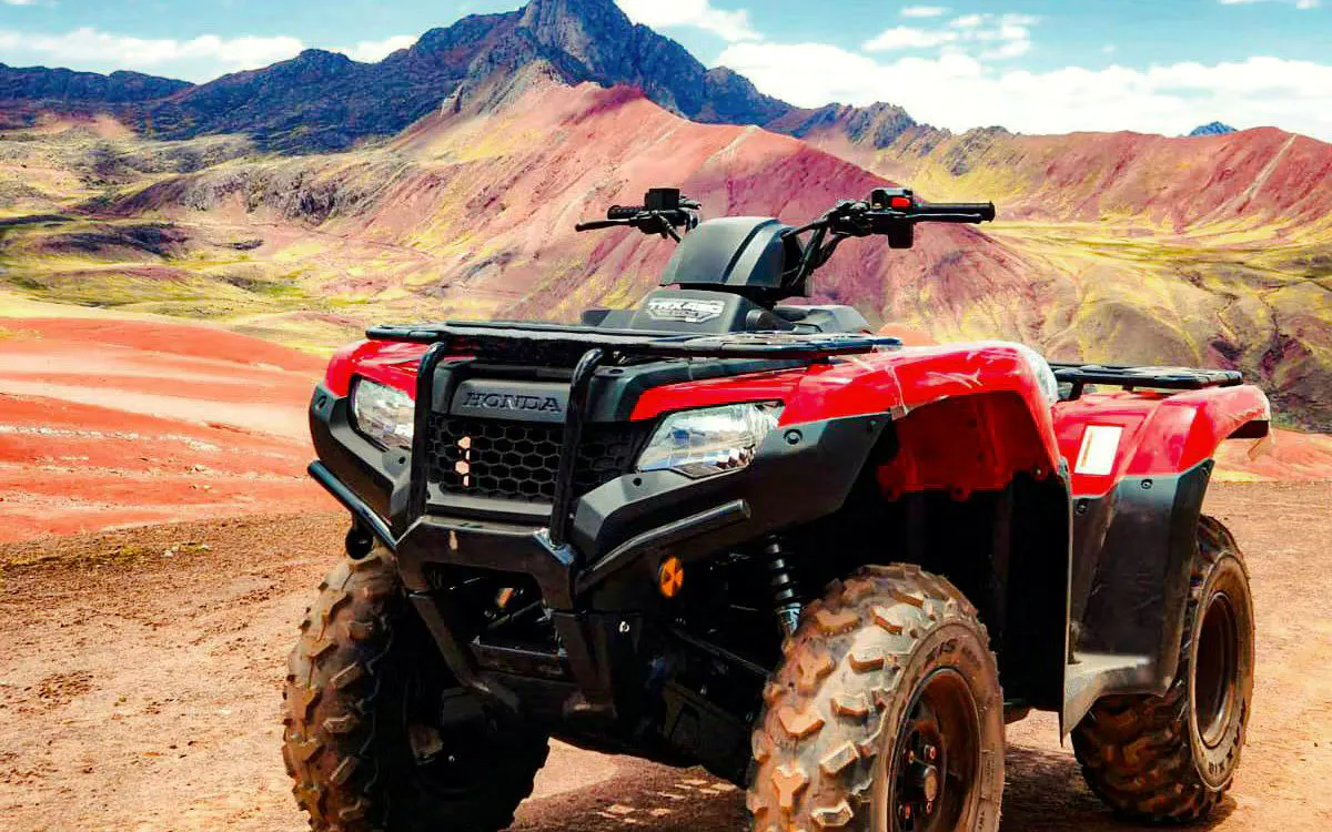 ATV parked in front of Rainbow Mountain and Red Valley landscape in Peru.