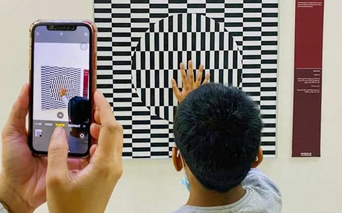 Child interacting with optical illusion exhibit at Museum of Illusions Dubai.