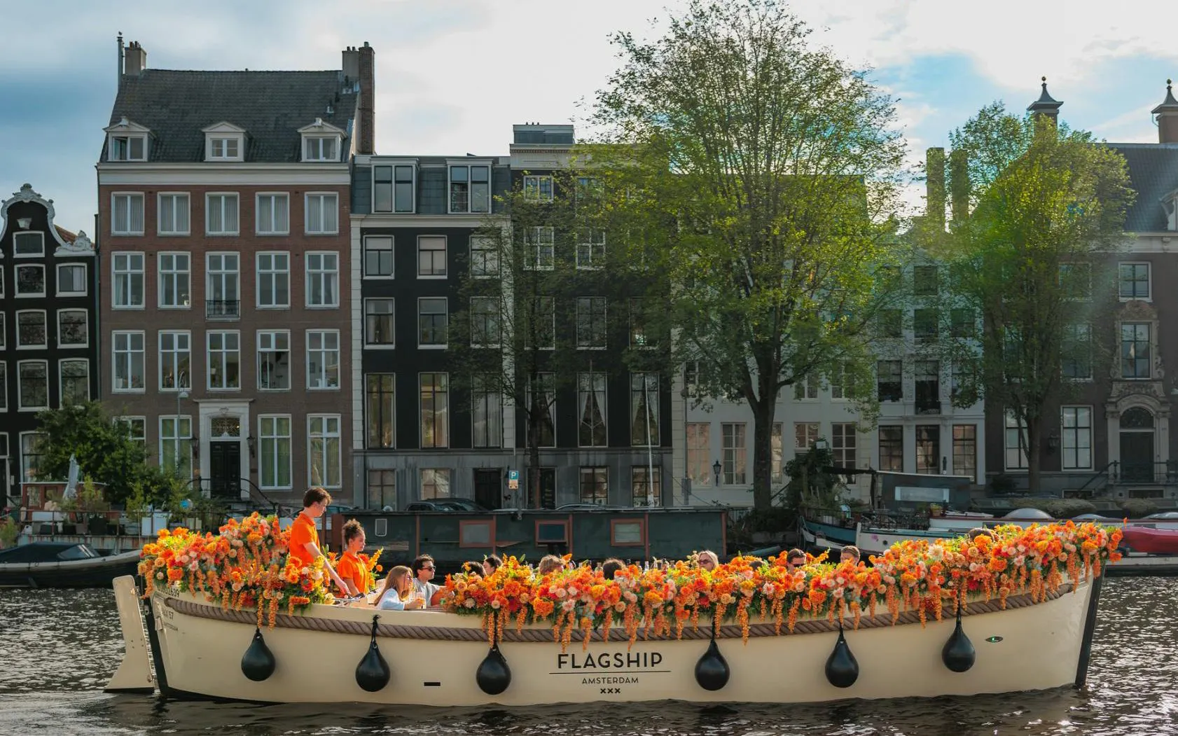 Guests enjoying a flower-adorned boat cruise on an Amsterdam canal.