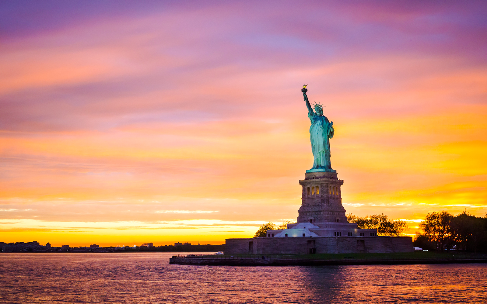 Statue of Liberty at sunset with vibrant sky, New York City.