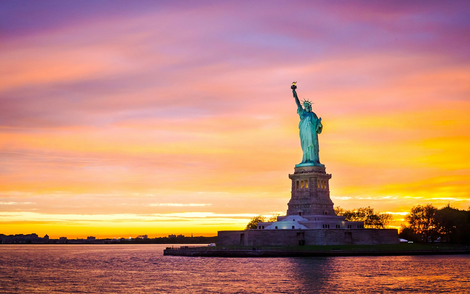 Statue of Liberty at sunset with vibrant sky, New York City.