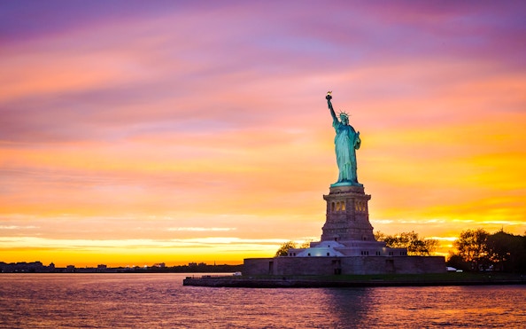 Statue of Liberty at sunset with vibrant sky, New York City.