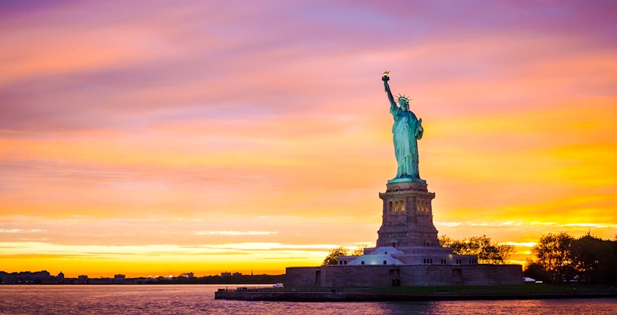 Statue of Liberty at sunset with vibrant sky, New York City.