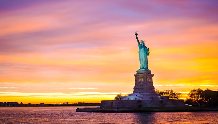 Statue of Liberty at sunset with vibrant sky, New York City.