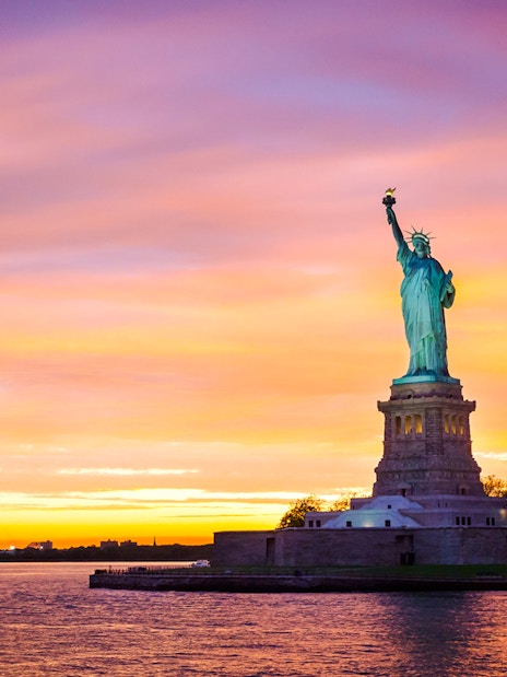 Statue of Liberty at sunset with vibrant sky, New York City.