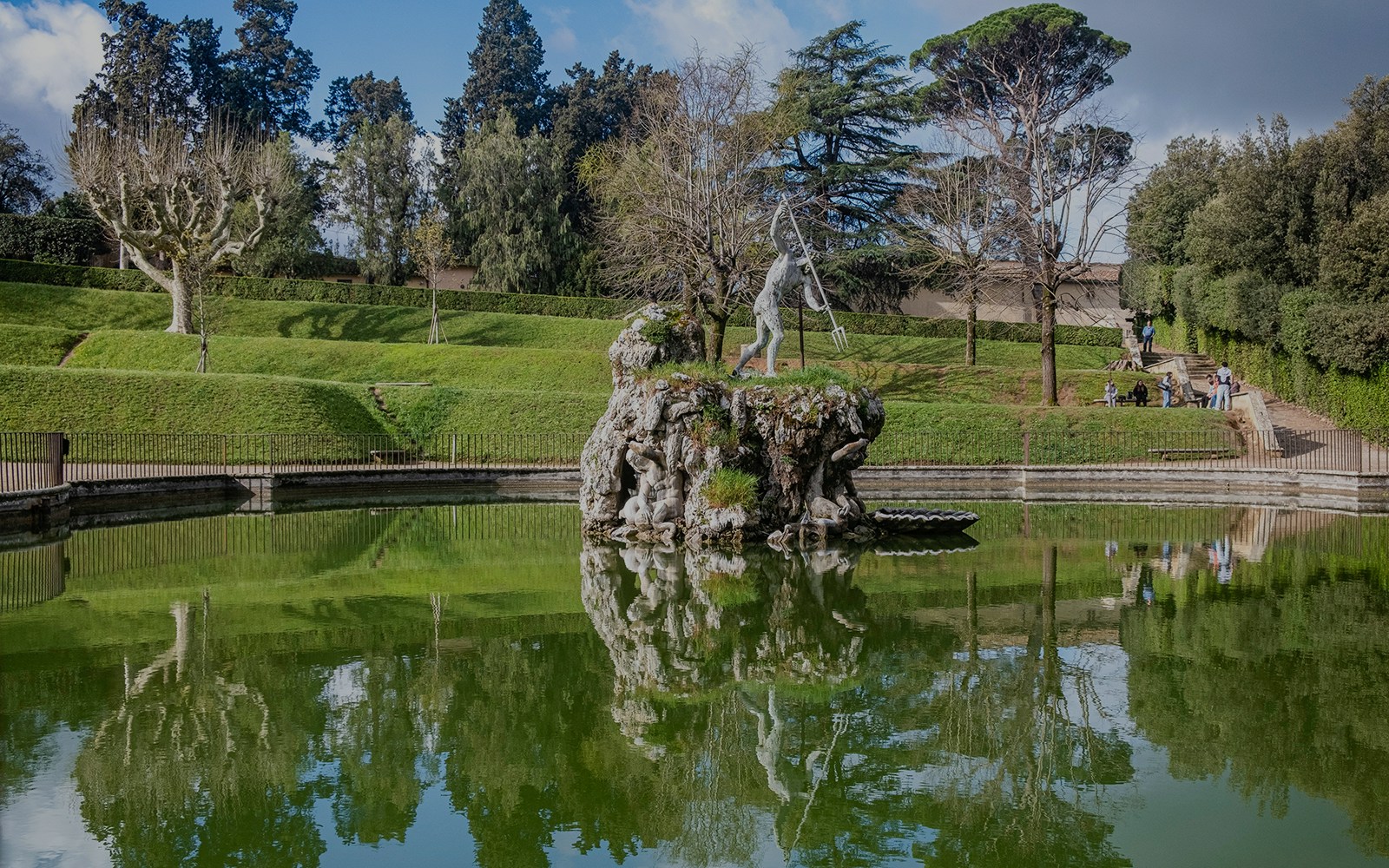 Sculpture in Boboli Gardens, Florence, reflected in a pond with surrounding greenery.