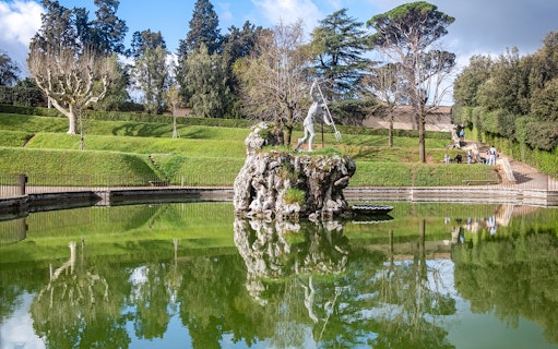 Sculpture in Boboli Gardens, Florence, reflected in a pond with surrounding greenery.