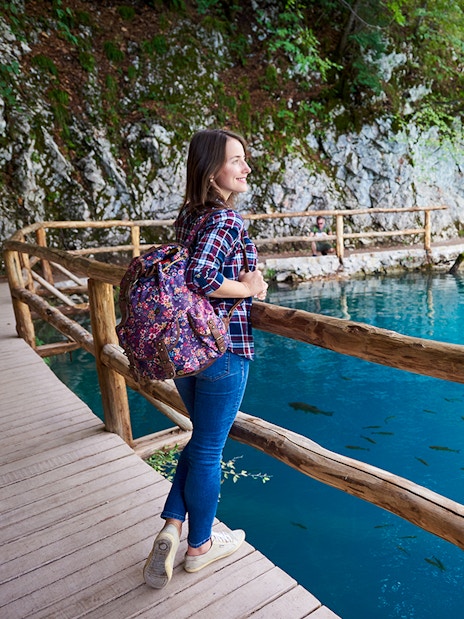 Guest walking along wooden path by turquoise lake at Plitvice Lakes National Park.