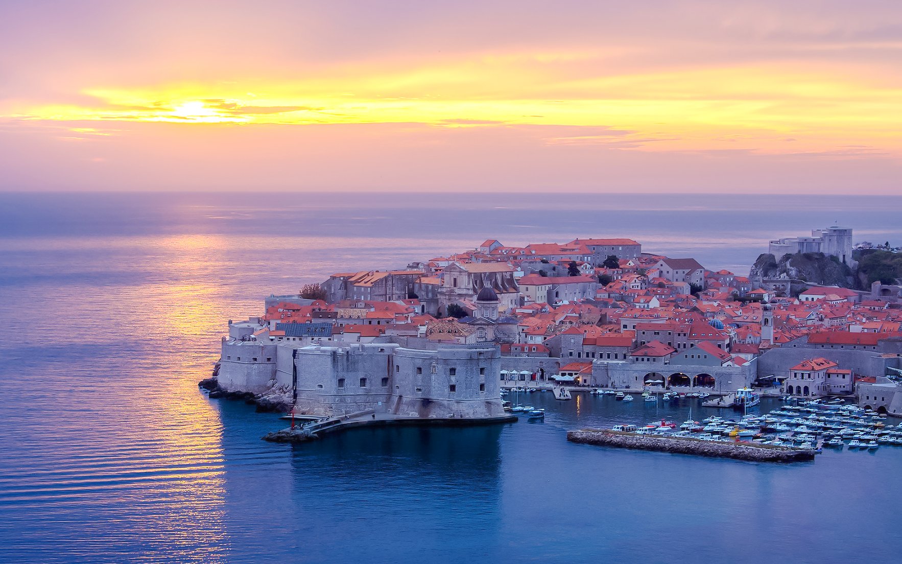Dubrovnik Old Town at sunset with city walls and Adriatic Sea.