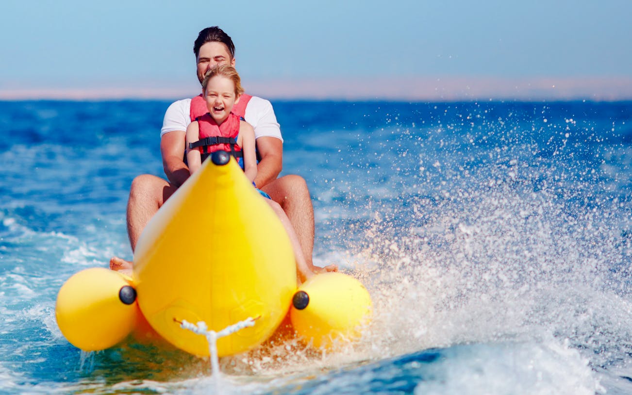 Family riding a banana boat on the sea in Dubai.