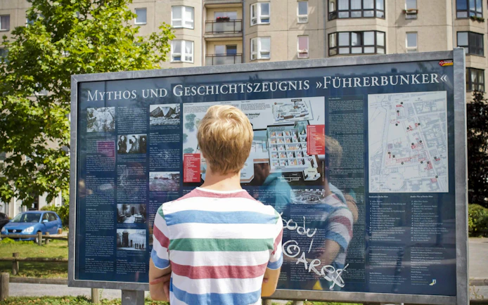 Visitor reading information board about Führerbunker in Berlin.