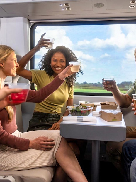 Group enjoying drinks on a train during Miami trip with open top bus and islands boat cruise.