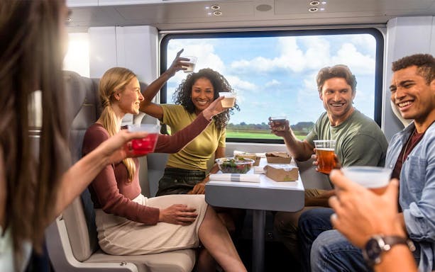 Group enjoying drinks on a train during Miami trip with open top bus and islands boat cruise.