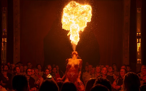 Performer breathing fire on stage at La Clique show.