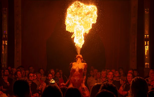 Performer breathing fire on stage at La Clique show.