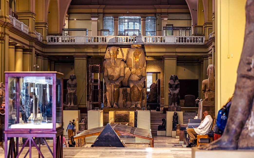 Grand Egyptian Museum interior with large ancient statues and display cases.
